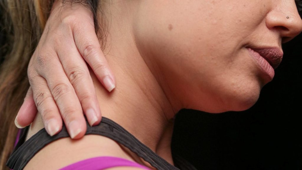 Woman holding her neck and shoulder in pain